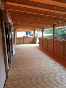 Vue intérieure de la terrasse couverte et fermée. Joues et façade sur rail avec porte relevable.