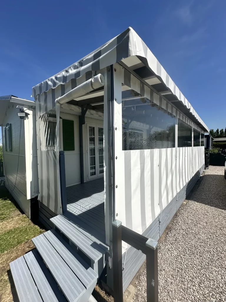 Terrasse de mobil home fermée par des bâches rayées grises et blanches