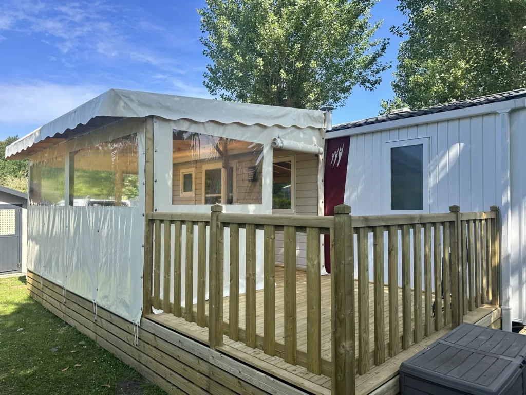 Terrasse de mobil home semi-couverte : partie fermée par une joue et une façade, partie ouverte avec garde-corps
